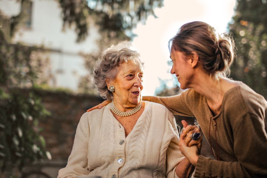 Senior woman laughing with her caregiver outdoors